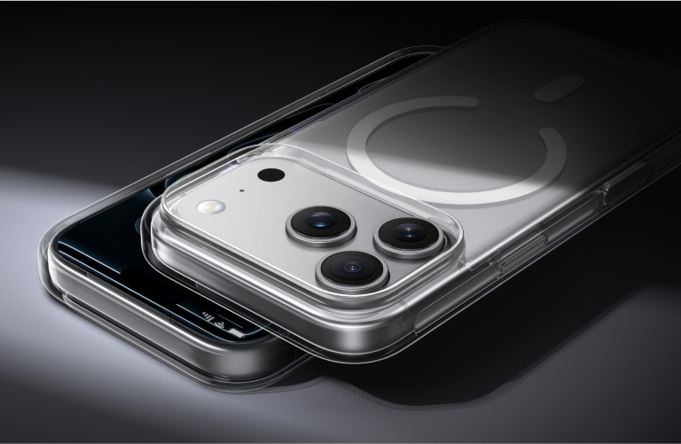 Close-up of two iPhones stacked on top of each other, both in clear MagSafe-compatible cases, highlighting the camera lenses and magnetic ring design against a dark background.