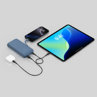 A Belkin portable power bank charging an iPhone, iPad, and wireless earbuds simultaneously via USB-C cables, all devices showing 9:41 on their screens.